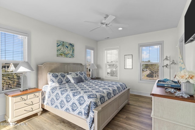 bedroom featuring a ceiling fan, visible vents, wood finished floors, and baseboards