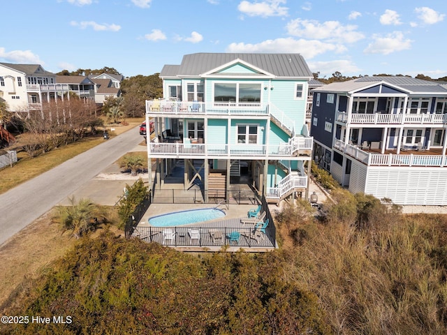 rear view of house with fence, stairway, a fenced in pool, a balcony, and a patio area