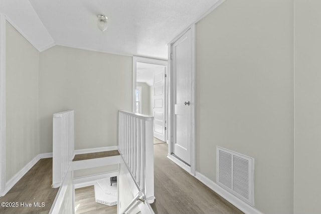 corridor with vaulted ceiling and hardwood / wood-style flooring