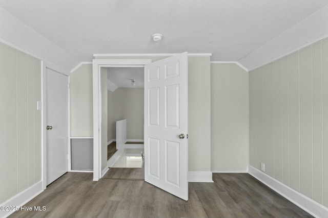 unfurnished bedroom featuring lofted ceiling, crown molding, and dark wood-type flooring