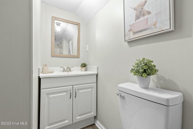 bathroom featuring vanity, toilet, and lofted ceiling