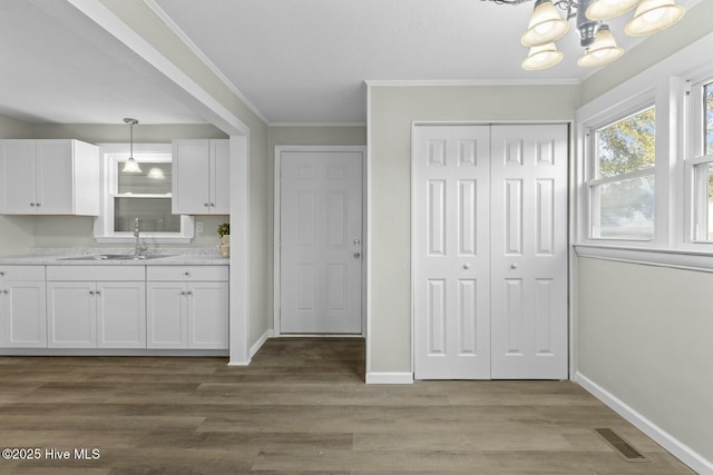 kitchen with crown molding, sink, pendant lighting, hardwood / wood-style flooring, and white cabinetry