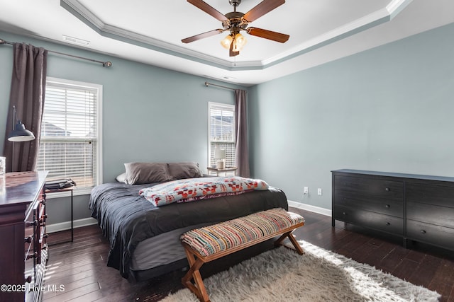 bedroom featuring dark hardwood / wood-style flooring, a tray ceiling, ceiling fan, and crown molding