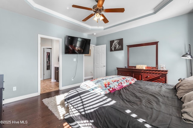 bedroom with dark hardwood / wood-style flooring, a tray ceiling, ceiling fan, and ornamental molding