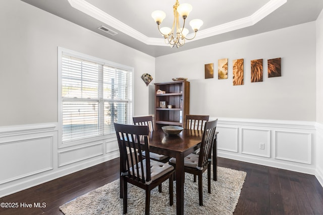 dining space with a raised ceiling, crown molding, dark hardwood / wood-style flooring, and a notable chandelier