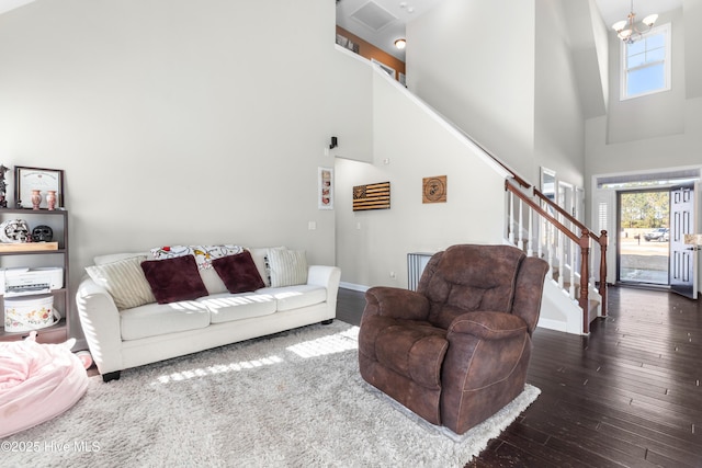 living room featuring a towering ceiling, dark wood-type flooring, and a notable chandelier