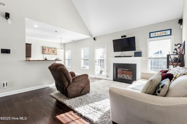 living room featuring a chandelier, high vaulted ceiling, and dark wood-type flooring