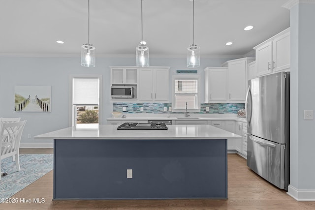 kitchen featuring stainless steel appliances, white cabinetry, hanging light fixtures, and a center island