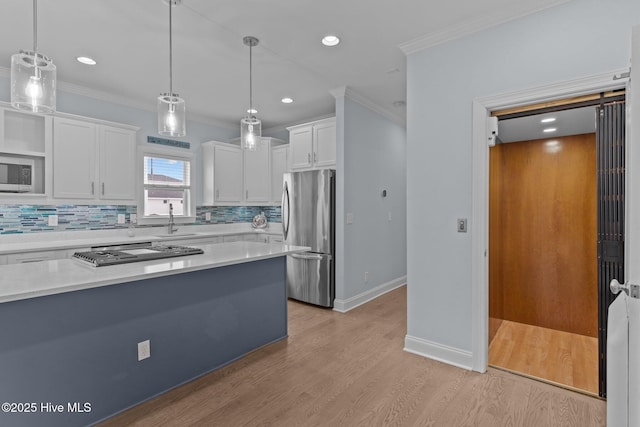 kitchen with white cabinetry, stainless steel appliances, sink, and hanging light fixtures