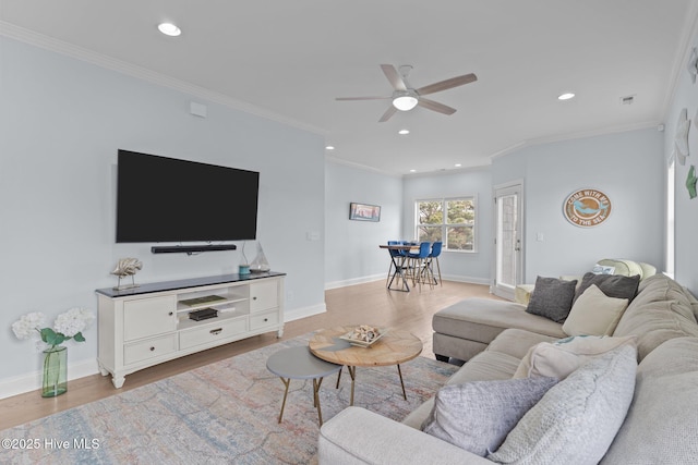 living room featuring ceiling fan, ornamental molding, and light hardwood / wood-style flooring