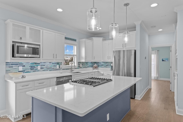 kitchen featuring decorative light fixtures, a kitchen island, white cabinets, and appliances with stainless steel finishes