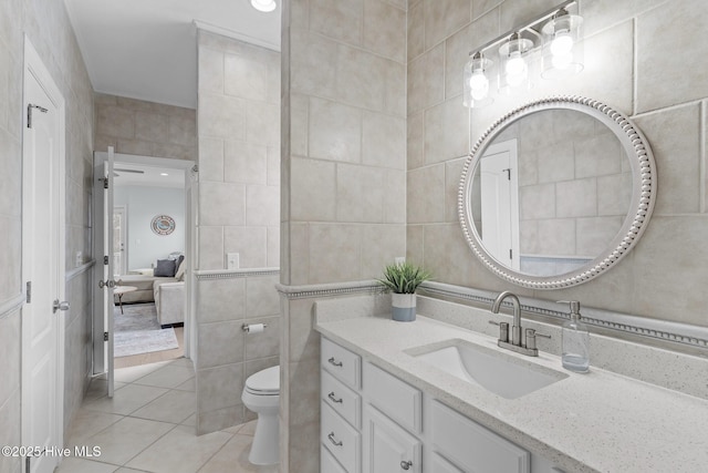 bathroom with tile patterned floors, toilet, tile walls, and vanity