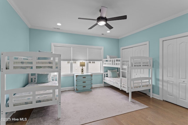 bedroom with multiple closets, ceiling fan, ornamental molding, and light hardwood / wood-style floors