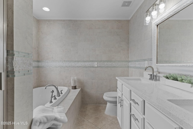 bathroom featuring tile walls, tile patterned flooring, vanity, a relaxing tiled tub, and toilet