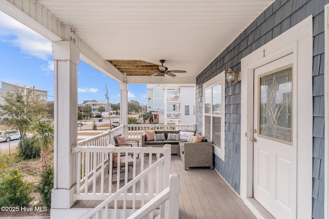 wooden terrace with an outdoor living space, ceiling fan, and covered porch