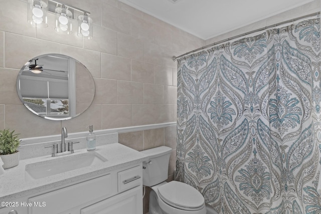 bathroom featuring toilet, a shower with curtain, tile walls, vanity, and ceiling fan