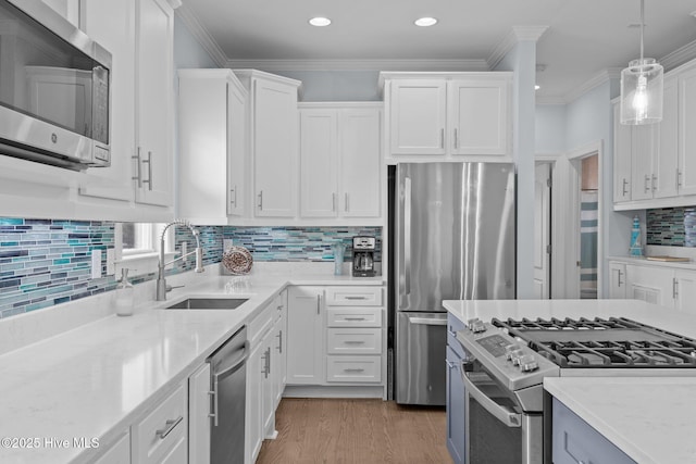 kitchen featuring appliances with stainless steel finishes, pendant lighting, sink, white cabinets, and crown molding