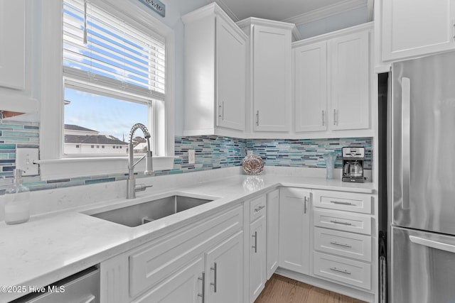 kitchen with sink, backsplash, stainless steel appliances, light stone countertops, and white cabinets