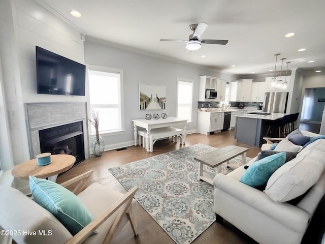 living room featuring ornamental molding, wood-type flooring, a wealth of natural light, and ceiling fan