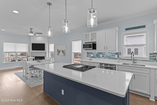 kitchen with sink, white cabinetry, decorative light fixtures, a center island, and appliances with stainless steel finishes