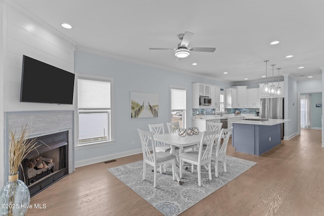 dining room with crown molding, light wood-type flooring, and a wealth of natural light