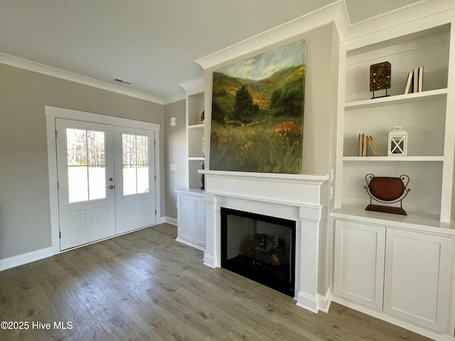 unfurnished living room with french doors, light hardwood / wood-style flooring, built in features, and crown molding