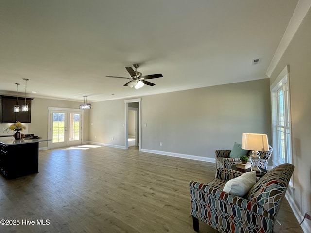 sitting room with french doors, ornamental molding, ceiling fan with notable chandelier, and hardwood / wood-style flooring