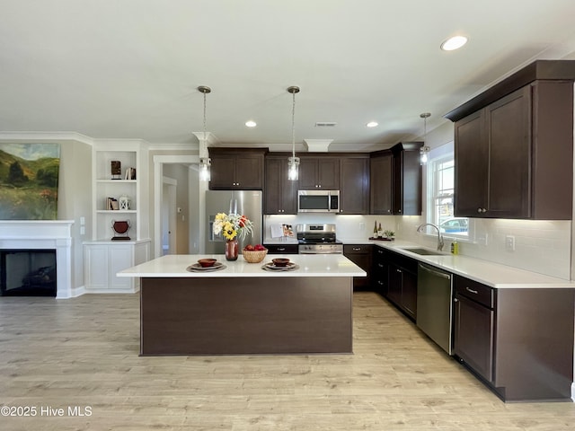 kitchen featuring pendant lighting, a kitchen island, stainless steel appliances, and light wood-type flooring