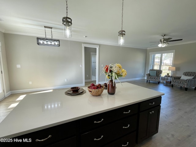 kitchen with ornamental molding, ceiling fan, decorative light fixtures, light hardwood / wood-style floors, and a kitchen island