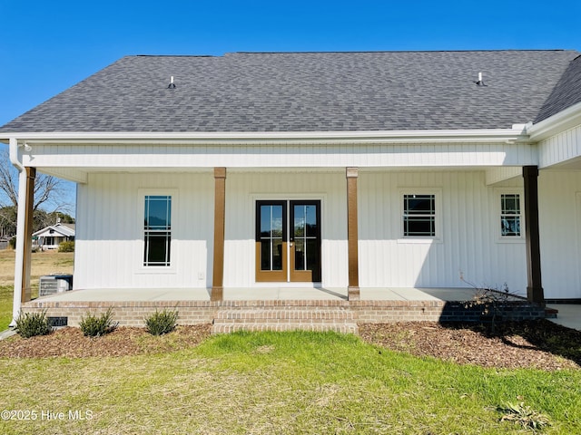 back of property with covered porch and a yard