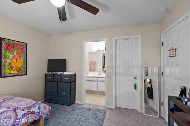 bedroom featuring ensuite bathroom, sink, ceiling fan, a textured ceiling, and light colored carpet