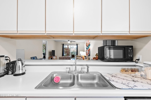 kitchen with white cabinetry, sink, and ceiling fan