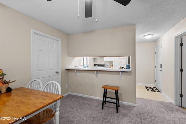 kitchen with a breakfast bar, ceiling fan, kitchen peninsula, and light carpet