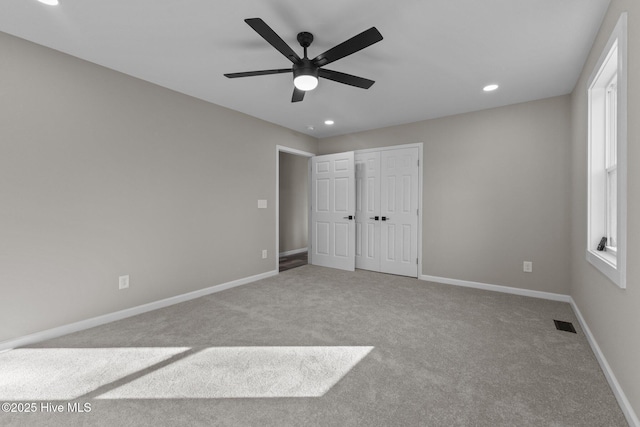 unfurnished bedroom featuring a closet, light colored carpet, and ceiling fan