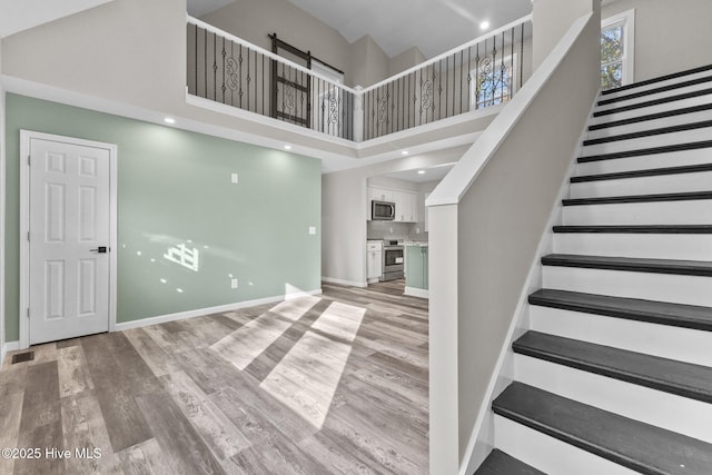 stairs with hardwood / wood-style floors and a high ceiling