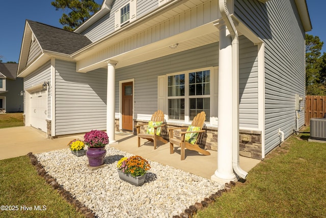 back of house with covered porch, a garage, and central AC unit