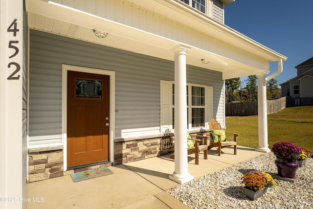 entrance to property featuring covered porch and a yard