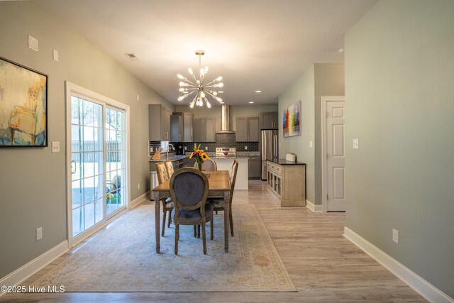 living room featuring ceiling fan with notable chandelier and light hardwood / wood-style flooring