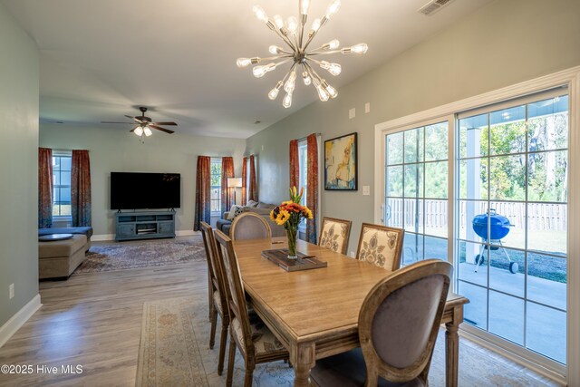 dining space featuring ceiling fan with notable chandelier and hardwood / wood-style flooring