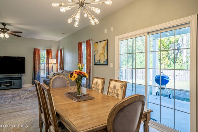 dining area with light wood-type flooring and ceiling fan with notable chandelier