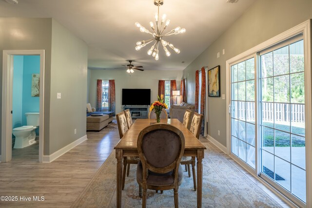 kitchen with dark stone counters, decorative light fixtures, a center island, light hardwood / wood-style floors, and white cabinetry