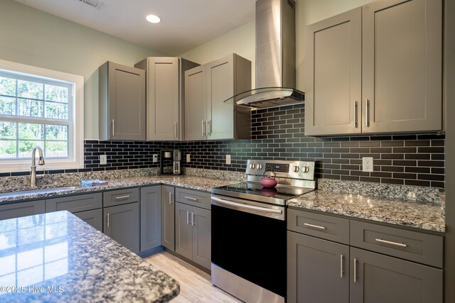 kitchen with gray cabinetry, sink, backsplash, light hardwood / wood-style floors, and appliances with stainless steel finishes