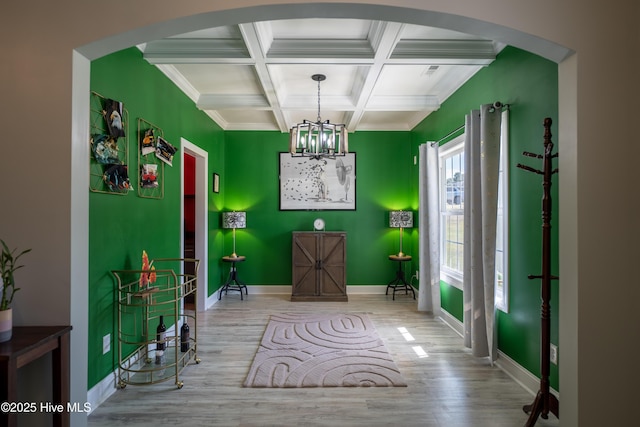 interior space with an inviting chandelier, beamed ceiling, coffered ceiling, and hardwood / wood-style flooring