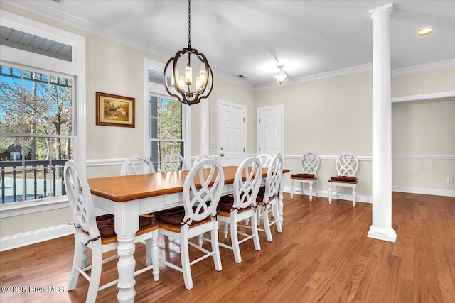 dining room featuring decorative columns, crown molding, a chandelier, and hardwood / wood-style flooring