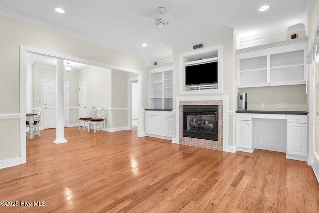 unfurnished living room featuring a fireplace, ceiling fan, built in features, and light wood-type flooring