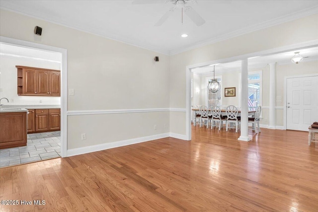 unfurnished living room featuring ceiling fan with notable chandelier, crown molding, light wood-type flooring, and sink