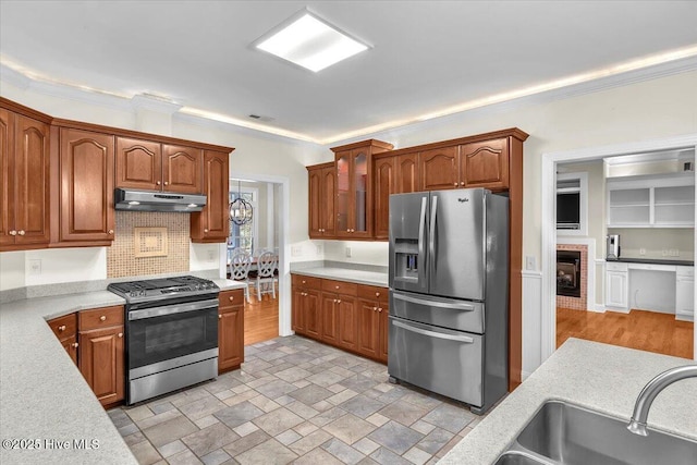 kitchen with ornamental molding, stainless steel appliances, and a brick fireplace