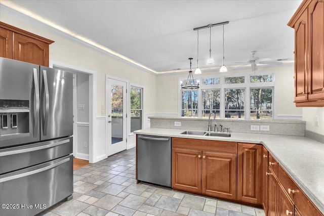 kitchen featuring sink, pendant lighting, appliances with stainless steel finishes, ceiling fan with notable chandelier, and ornamental molding