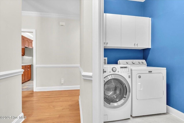 laundry area featuring cabinets, ornamental molding, light wood-type flooring, and washing machine and dryer