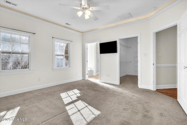 unfurnished bedroom with ceiling fan, light colored carpet, a spacious closet, and a closet